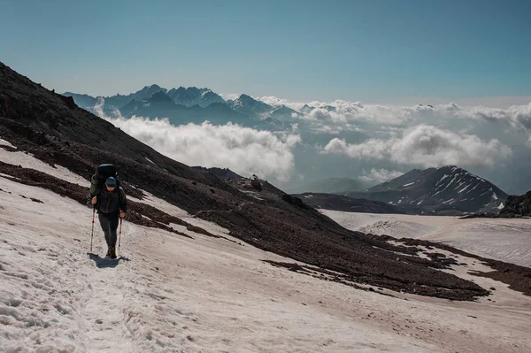 Hombre caminando en el sendero nevado mirando hacia abajo subiendo a la montaña — Foto de Stock