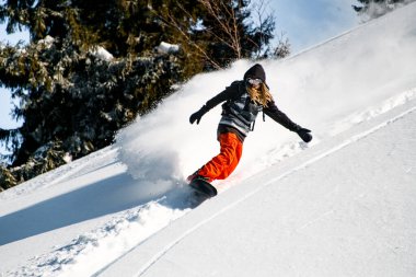 Freeride snowboardcusu karla kaplı yamaçta aşağı iniyor.