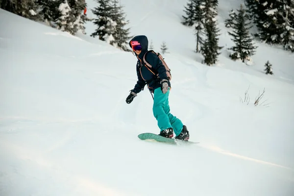 Dişi snowboardcu dağdan aşağıya karla kaplı yamaçta iniyor. — Stok fotoğraf