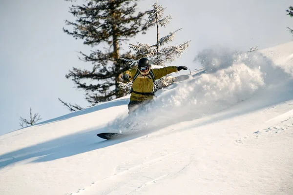 Facet zjeżdża na snowboardzie po stronie gór. — Zdjęcie stockowe