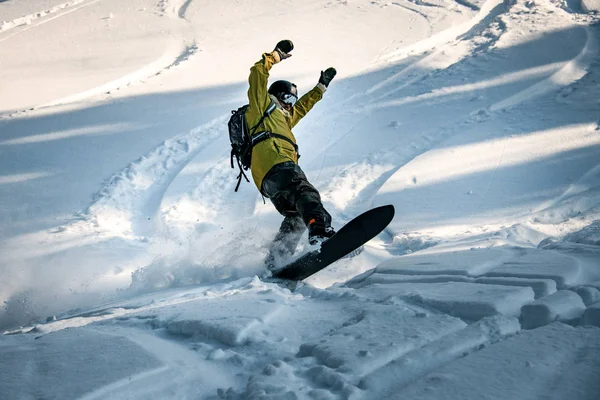 Homem freeride snowboarder saltando pela encosta coberta de neve da montanha — Fotografia de Stock