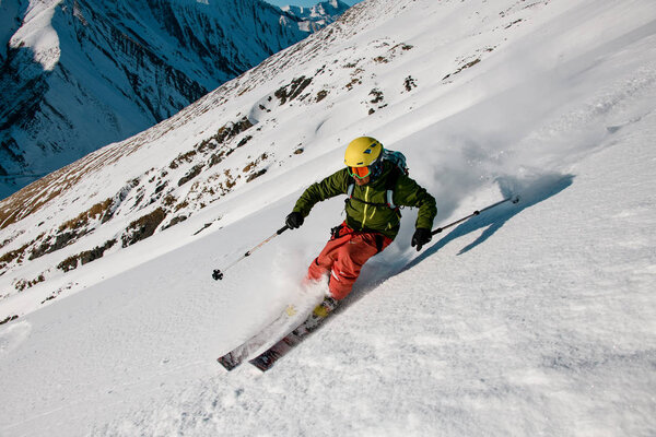 Man skier slides down on the mountain side
