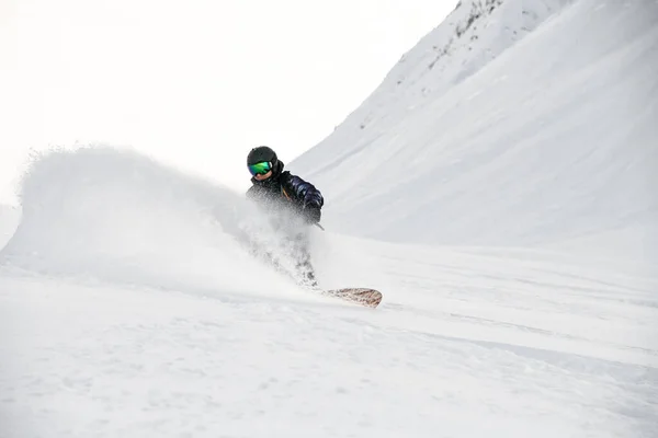 Freerider in full equipment rides on a snowboard in mountains — Stock Fotó