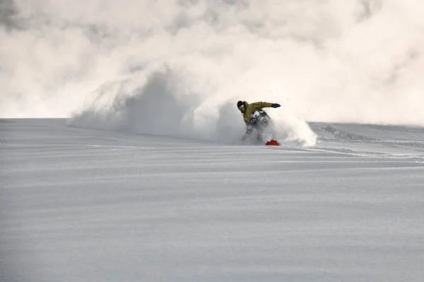 Man on a snowboard slides on a snowy mountain side — 스톡 사진