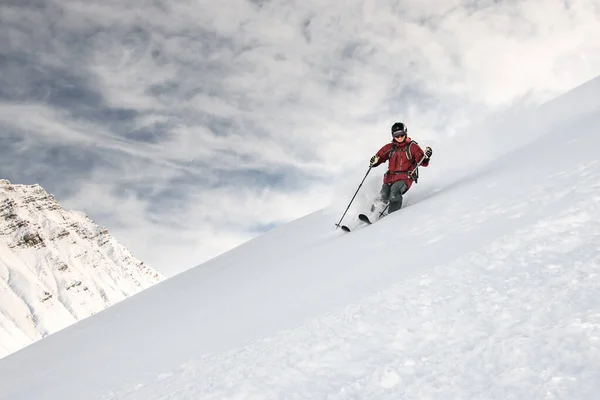 Smiling skiier slides down the mountain side — ストック写真