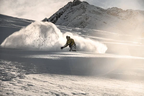 Homem snowboarder com rosto coberto de neve escorregando na montanha nevada — Fotografia de Stock