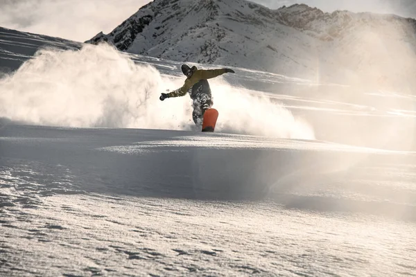 Homem snowboarder com rosto coberto de neve deslizando na montanha nevada — Fotografia de Stock