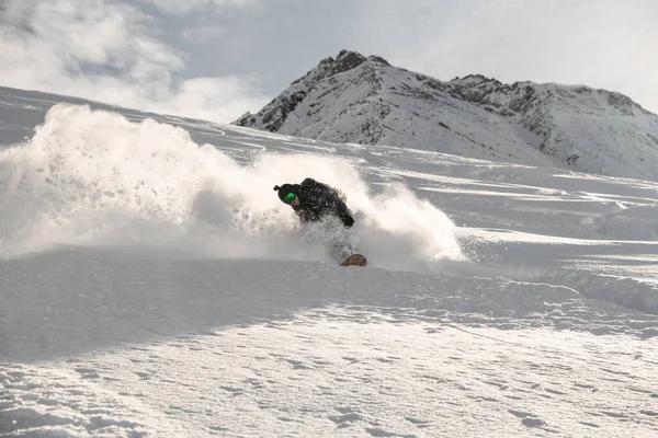 Un type sur un snowboard glissant sur une montagne enneigée — Photo