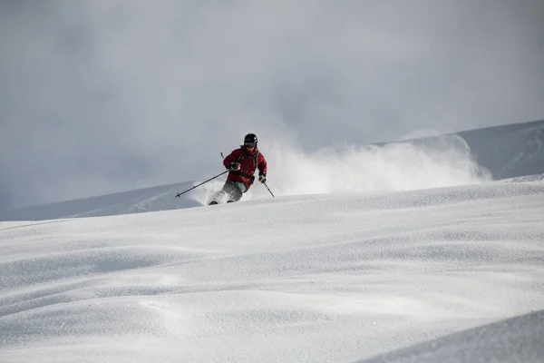 Homme sur un ski glissant sur une montagne enneigée — Photo