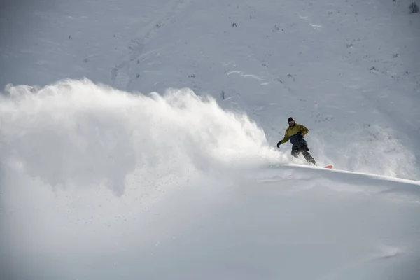 Hombre snowboarder se desliza en una tabla de snowboard en la distancia — Foto de Stock