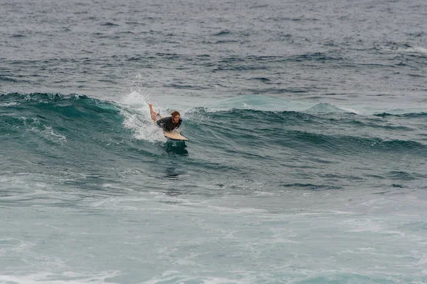 Hombre surfista se desliza en una tabla de surf en una ola — Foto de Stock