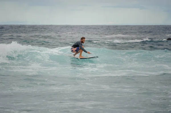Hombre surfista cabalgando en una tabla de surf en una ola — Foto de Stock
