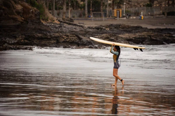 Surfista feminina com prancha na cabeça anda perto da costa — Fotografia de Stock