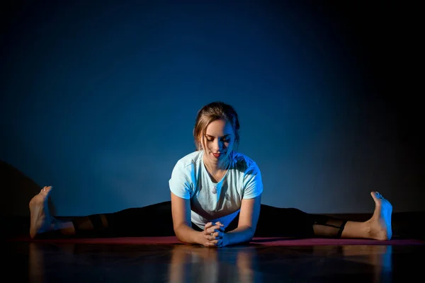 Девушка в спортивной одежде практикующая йогу в студии в растягивающейся позе — стоковое фото