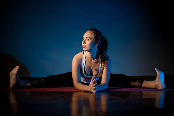 Mujer con ropa deportiva practicando yoga en una sala de estudio en la pose de estiramiento — Foto de Stock