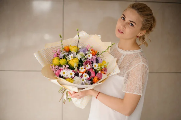 Girl holding a spring bouquet of different color flowers with branches — Stockfoto