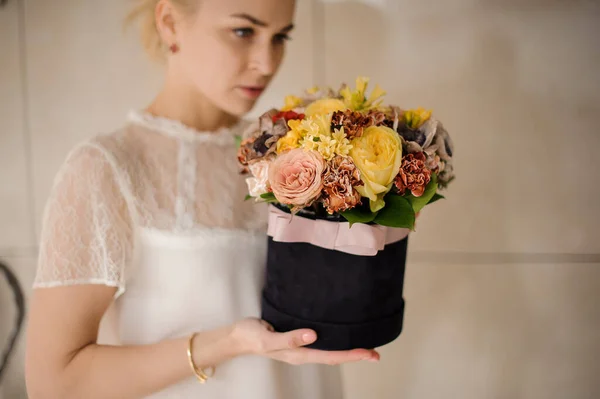 Ragazza che tiene una scatola di velluto nero di rose di peonia gialle e cremose decorate con un nastro — Foto Stock