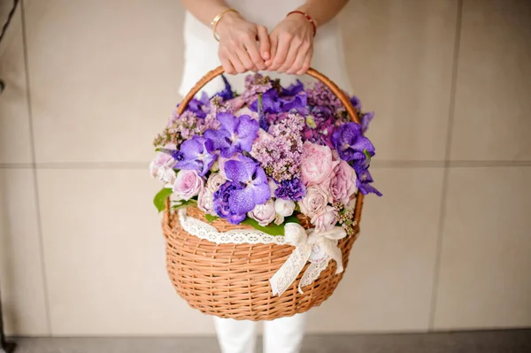 Menina segurando uma grande cesta de flores de cor tenra primavera da cor roxa e rosa — Fotografia de Stock