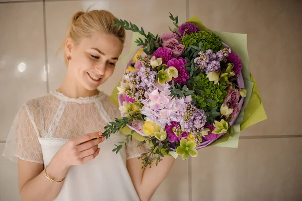 Menina segurando um buquê de primavera de flores verde, roxo e violeta concurso decorado com ramos de arbusto — Fotografia de Stock