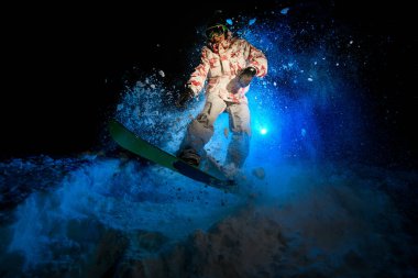 Darkened shot of male freerider jumping on snowboard