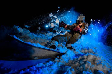GIrl snowboarder slides on a snowboard in night