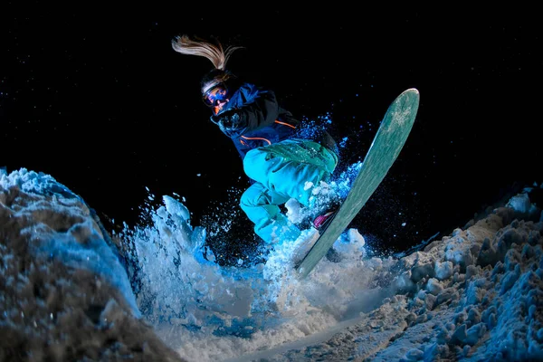 Mujer snowboarder haciendo acrobacias sobre fondo azul claro — Foto de Stock