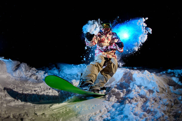 Guy in winter clothes rides on a snowboard