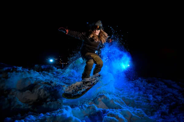 Female snowboarder slides on a snowboard in night — Stockfoto