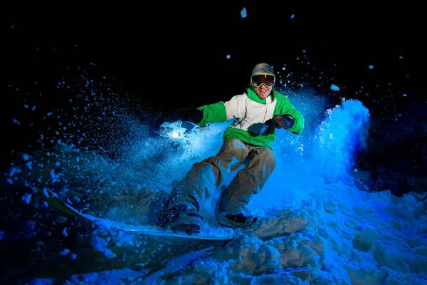 Guy in green jacket rides on a snowboard — Stockfoto