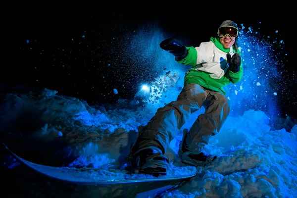 Male in green jacket rides on a snowboard — Stockfoto