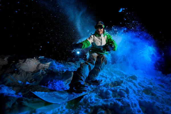 Smiling guy on a snowboard rides on snow — Stockfoto