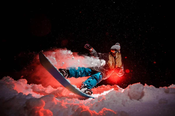 Woman glides on a snowboard on red light background
