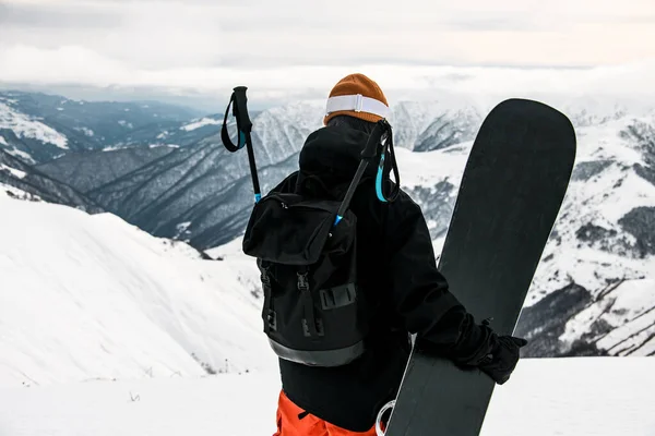 Male in winter sportswear with snowboard on mountain top — 图库照片