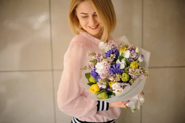 Mujer sonriente sosteniendo un hermoso ramo de flores de diferentes flores frescas . — Foto de Stock