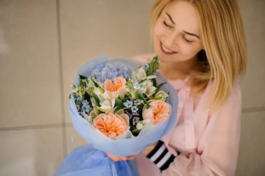 Gülümseyen kadın elinde farklı taze çiçeklerle güzel bir buket tutuyor..