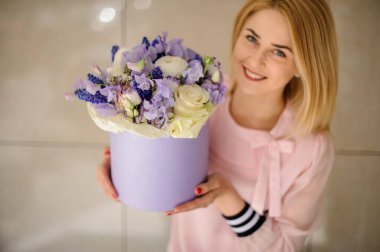 Gülümseyen sarışın kadın elinde güzel bir buket taze çiçek tutuyor.