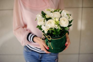 Beyaz ranunculus ve frezyalı yaratıcı çiçek kompozisyonu tutan kadın..