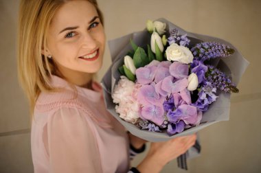 Gülen kadın elinde güzel bir çiçek buketi tutuyor..