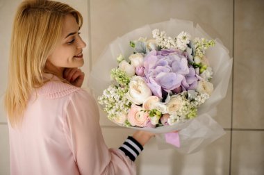 Bouquet of lilac hydrangea in the hands of a girl in a pink blouse.