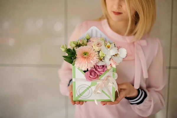 Piękna kompozycja z różnych kwiatów w pudełku dekoracyjnym w rękach kobiety — Zdjęcie stockowe