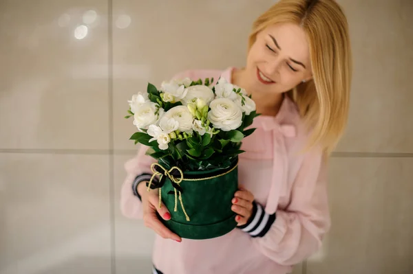 Jovem mulher segurando composição de flores em redondo caixa verde em suas mãos . — Fotografia de Stock
