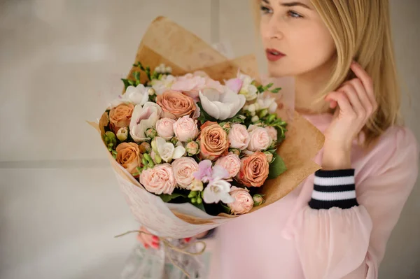 Młoda blondynka z bukietem kwiatów w pastelowych kolorach. — Zdjęcie stockowe