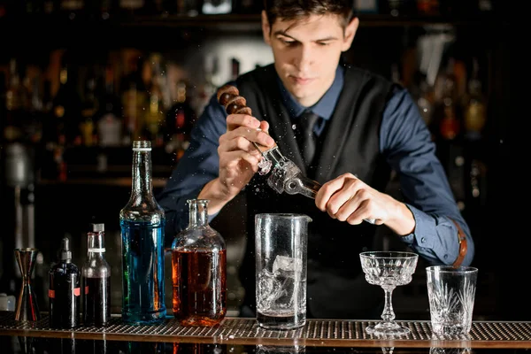 Bartender with special device breaks pieces of ice to make a cocktail. — Stockfoto