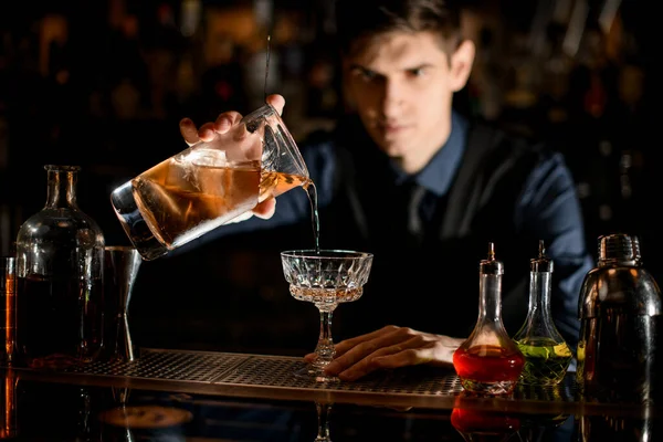 Barman gentilmente começa a derramar um coquetel em um copo de vinho — Fotografia de Stock