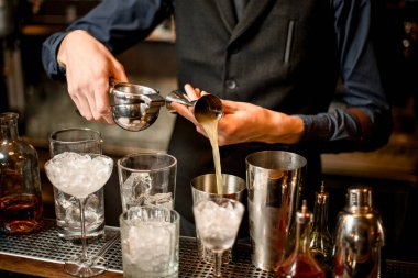 bartender pours squeezed juice from a beaker into a shaker