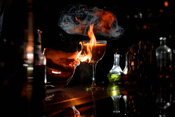 Close-up bartenders hands which sets fire near cocktail wineglass. — Stock Photo, Image