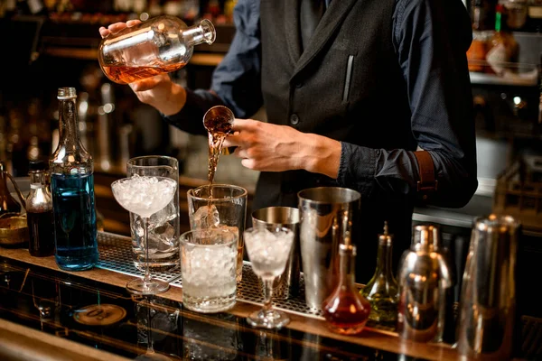 Professional bartender cook alcoholic cocktail with ice.