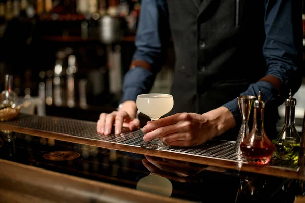 Barkeeper im blauen Hemd mit weißem Cocktail im Glas an der Bar — Stockfoto