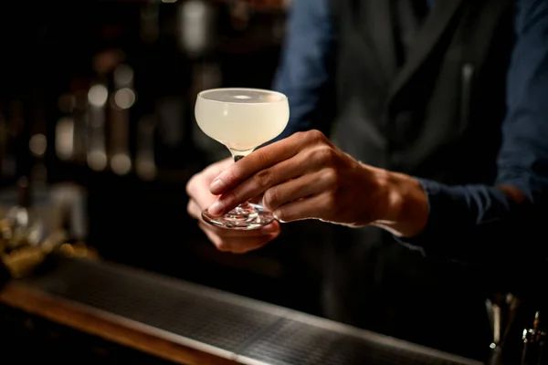 Barman segurando coquetel branco em vidro sobre o bar — Fotografia de Stock