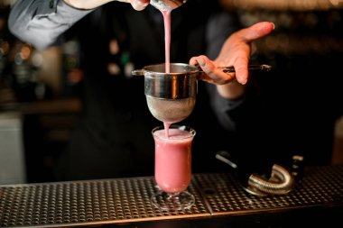 Barmenin elek kullanarak bardaktan cama nasıl kokteyl döktüğünü yakından çek..